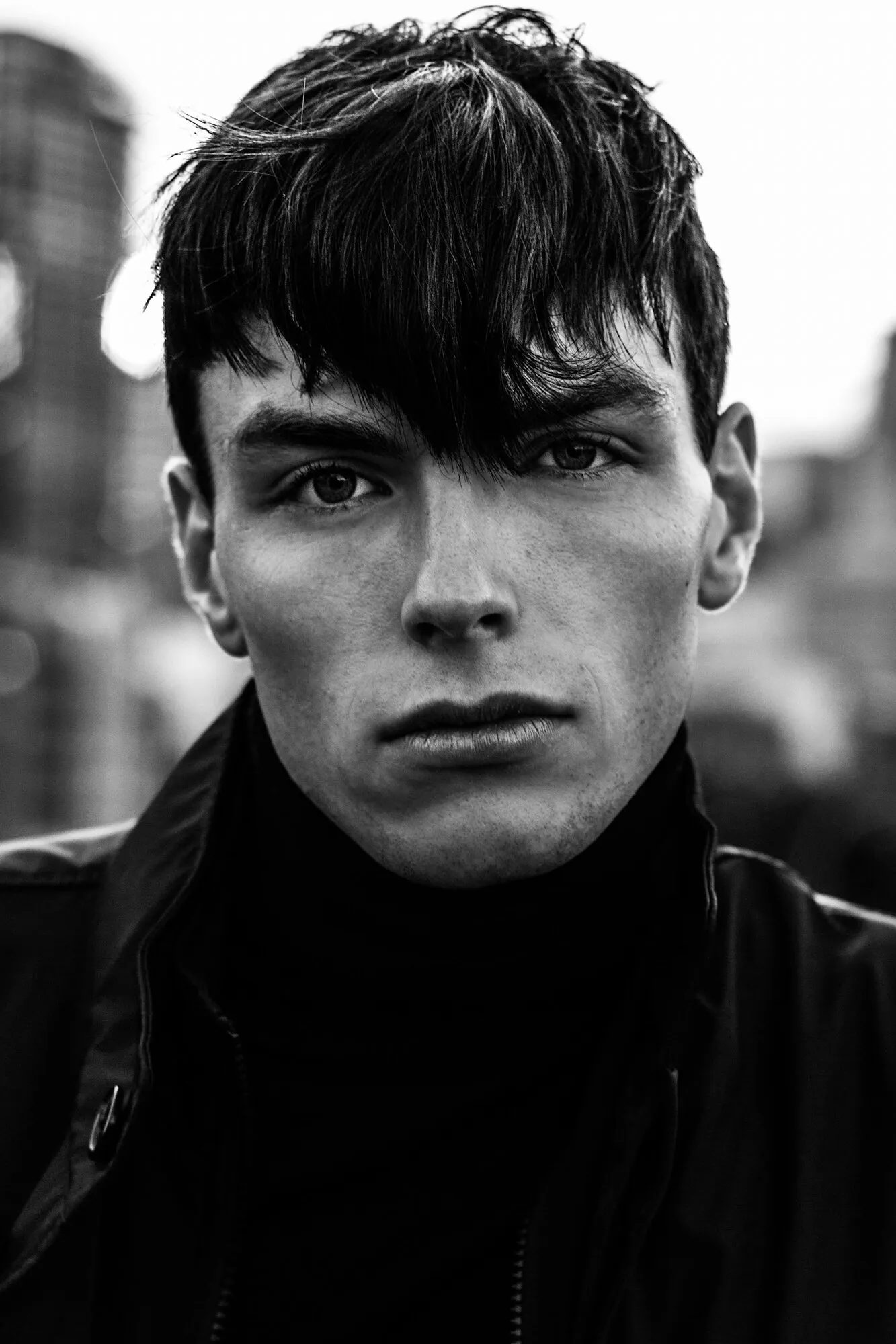 High-contrast black and white street portrait of a model with a dark fringe