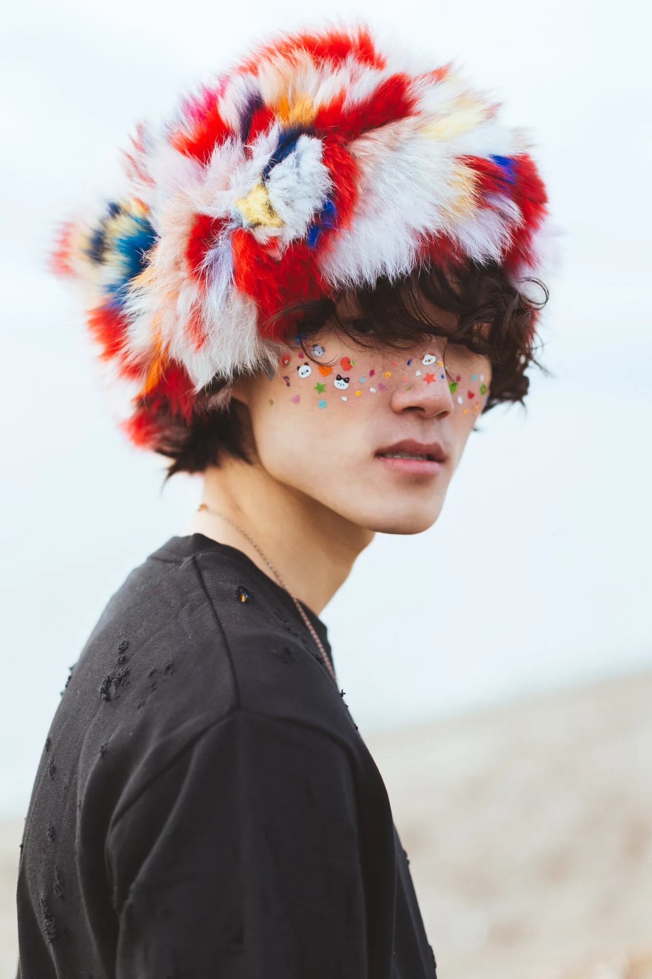 Model wearing a multicoloured fur hat with sequins beneath one eye