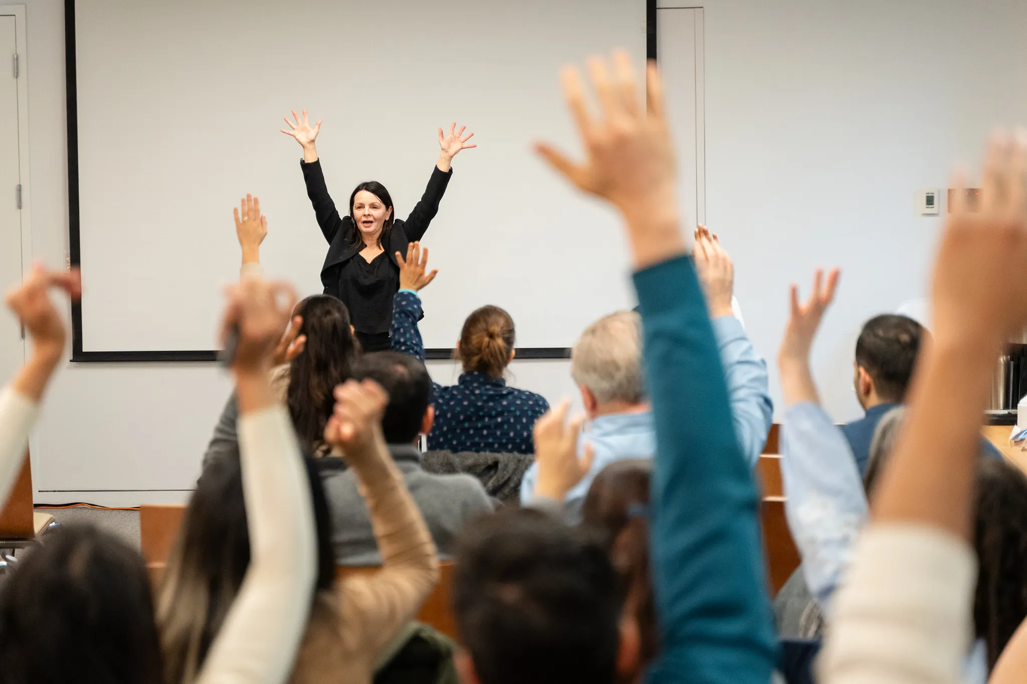 Presenter with arms raised as audience members raise their hands at Venture Founder C50 Session 15